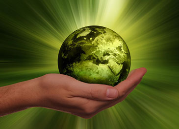 A hand holding a green Earth